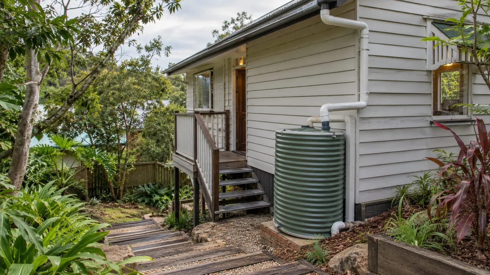 AI-generated illustration: Red Hill timber cottage on a sloping leafy Brisbane block, downpipe and stormwater collection beside steps