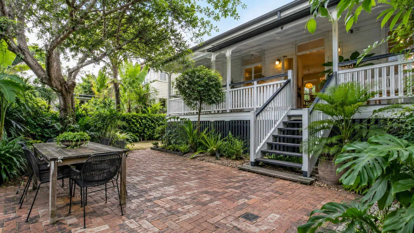 AI-generated illustration: New Farm renovated weatherboard Queenslander, shaded veranda, mature subtropical garden and brick courtyard drainage