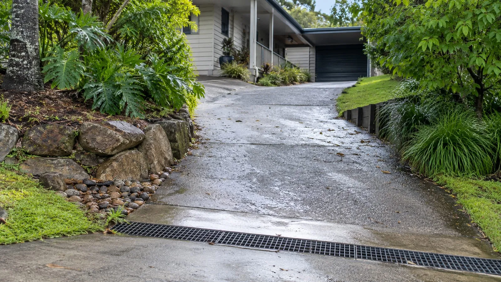AI-generated illustration: sloping driveway and surface-water collection on a leafy hills-edge block