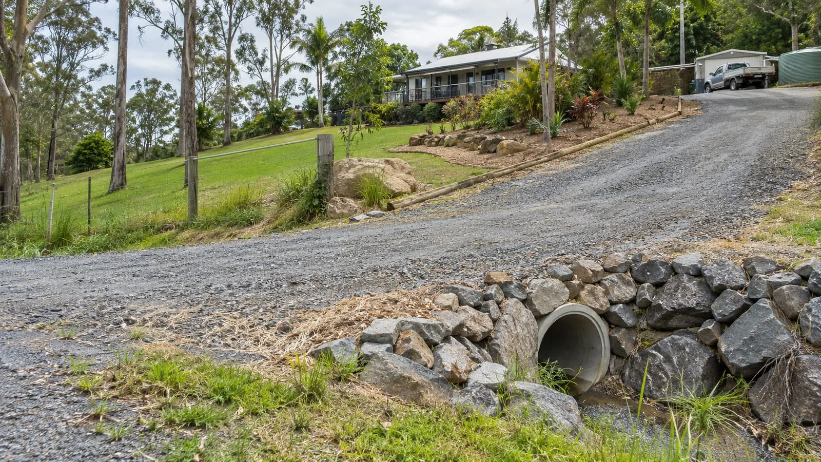 AI-generated illustration: hills-property driveway drainage and access across a larger block